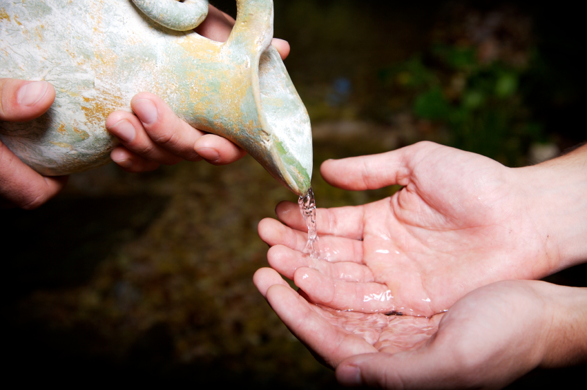 pouring fresh stream water out of a clay jug representing servanthood and christian service