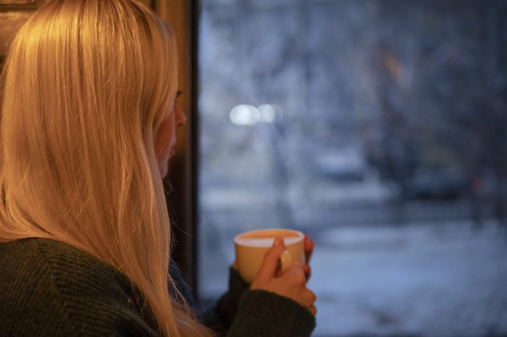 Woman holding coffee cup, looking out the window