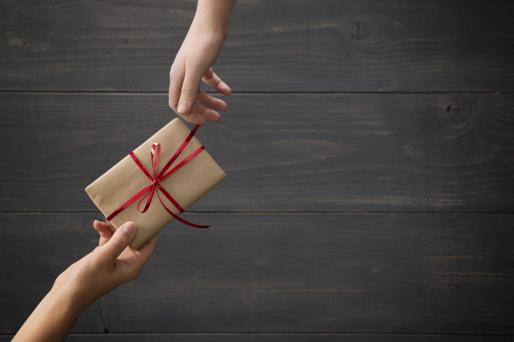 Person handing a small Christmas gift to someone