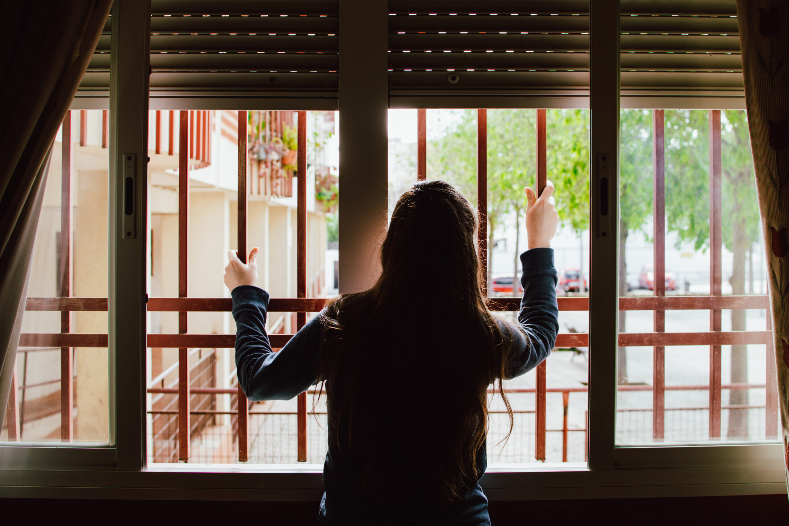 woman holding bars on window